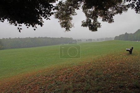 Téléchargez les photos : Vue d'un paysage vallonné et brumeux avec banc en Bavière, Allemagne - en image libre de droit