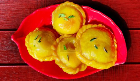 Téléchargez les photos : Un Diwali indien Sweet Food Chandrakala Gujia est fabriqué avec Maida pour la couverture extérieure et Khoya, noix sur la table en bois de couleur rouge - en image libre de droit