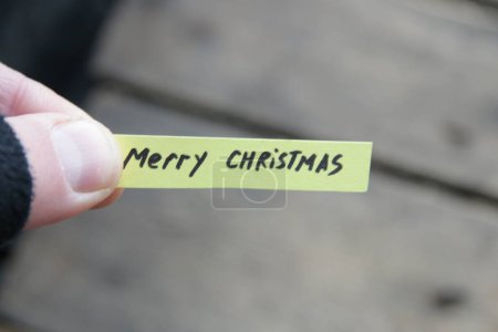 Photo for Merry Christmas, the inscription on the tag on the background of the old vintage table. - Royalty Free Image