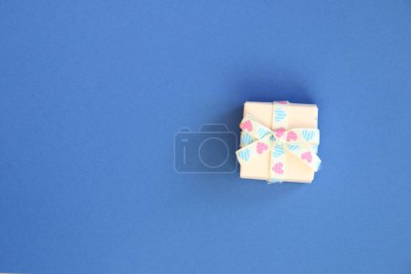 Photo for Holiday gift box or present with bow ribbon on a blue background. - Royalty Free Image