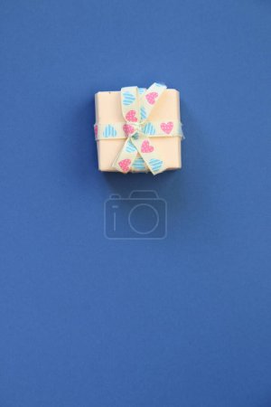 Photo for Holiday gift box or present with bow ribbon on a blue background. - Royalty Free Image