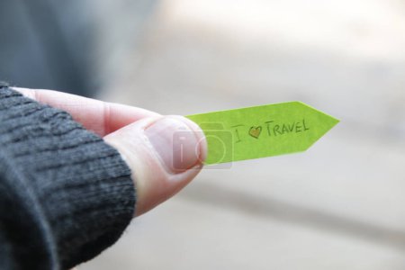 Foto de Me encanta viajar, concepto creativo. Una mano sostiene una etiqueta con una inscripción. - Imagen libre de derechos