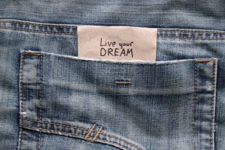 Téléchargez les photos : Vivez votre concept de rêve. Citations motivantes inscription sur une étiquette dans une poche de jeans bleus. - en image libre de droit