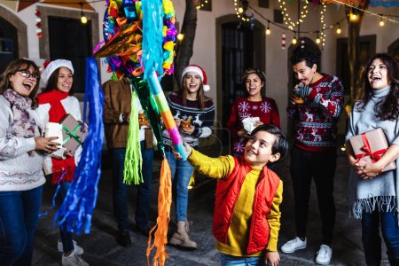 Photo for Hispanic family breaking a pinata at traditional mexican posada celebration for Christmas in Mexico Latin America - Royalty Free Image