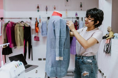 Foto de Young hispanic woman fashion designer stylish working with mannequins standing and colorful fabrics at fashion studio in Mexico Latin America - Imagen libre de derechos