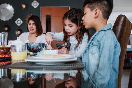 Téléchargez les photos : Fils et fille de la famille latine prenant le petit déjeuner et la nourriture mexicaine à la maison au Mexique, enfants hispaniques en Amérique latine - en image libre de droit
