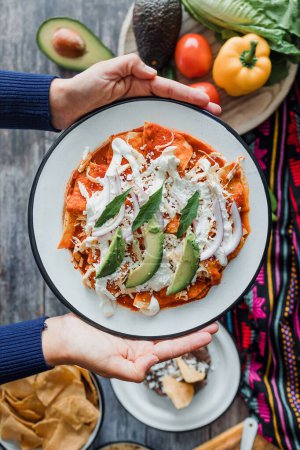 Mexican chilaquiles food with spicy red sauce, chicken and avocado traditional breakfast in Mexico Latin America