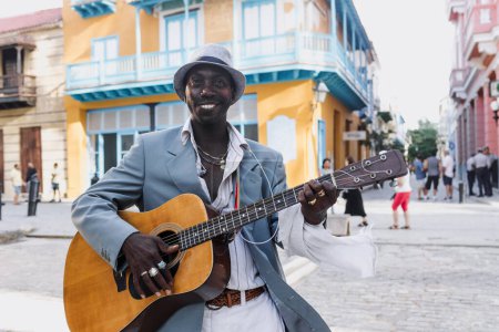Photo for Black Man musician playing guitar on the street in La Havana in Latin America, Afro american and caribbean people - Royalty Free Image