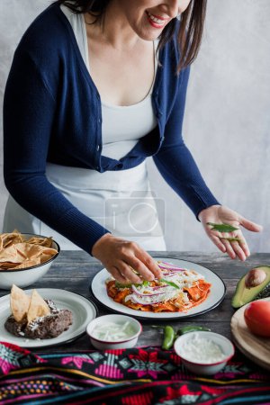 Téléchargez les photos : Mexican woman preparing chilaquiles with red sauce and eating traditional mexican food for breakfast in Mexico Latin America, hispanic people - en image libre de droit