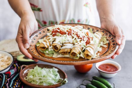 Photo for Mexican woman cooking tacos dorados called flautas with chicken, traditional fried food in Mexico Latin America - Royalty Free Image