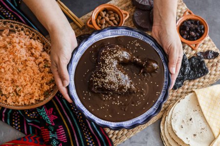 Photo for Mexican woman cooking mole poblano sauce with chicken traditional food in Mexico Latin America - Royalty Free Image