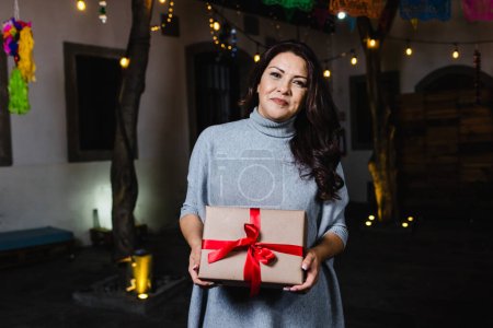 Hispanic young woman portrait holding a gif box at traditional posada party for Christmas in Mexico Latin America