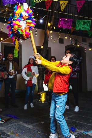 Latin family breaking a pinata at traditional mexican posada celebration for Christmas eve in Mexico Latin America