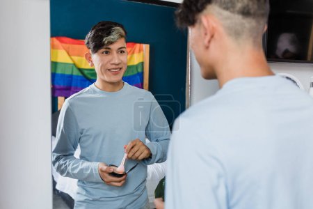 Junger lateinischer homosexueller Mann schminkt sich mit Spiegel im Schlafzimmer zu Hause in Mexiko, hispanische homosexuelle und lgbtq Gemeinschaft in Lateinamerika