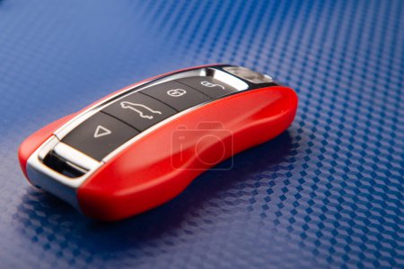 Téléchargez les photos : The key to the sports car is red, lies on a blue background. - en image libre de droit