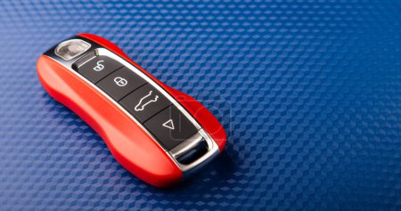 Foto de The key to the sports car is red, lies on a blue background. - Imagen libre de derechos