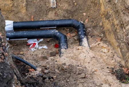 Black pipes in the ground and sand. Installation of sewer pipes in the city. close up