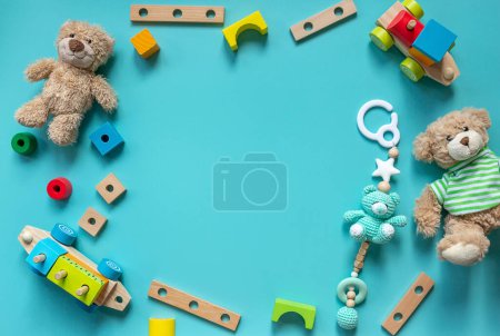 Teddy bear, wooden toys, blocks for preschooler children on a blue background. Toys for kindergarten, preschool or daycare. Copy space for text. Top view, close up