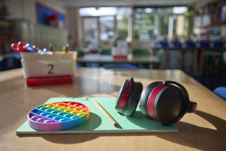 Foto de Defensores de oídos o auriculares y juguete Fidget para ayudar a los niños con ASD o autismo en la mesa en el aula de la escuela - Imagen libre de derechos