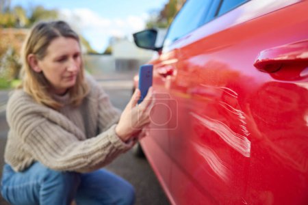 Téléchargez les photos : Femme mûre conducteur prenant des photos de dommages à la voiture après un accident sur téléphone portable - en image libre de droit