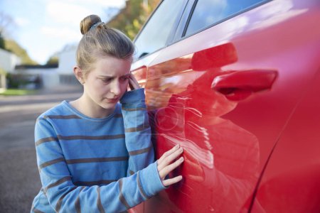 Foto de Joven adolescente preocupado conductor femenino mirando coche dañado después de accidente - Imagen libre de derechos