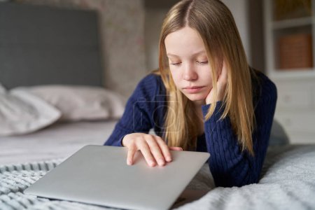 Photo for Unhappy Teenage Girl Closing Laptop Lying On Bed At Home Anxious About Social Media Online Bullying And Being Online Too Much - Royalty Free Image