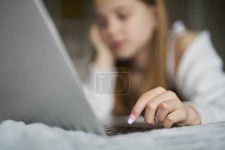 Photo for Close Up Teenage Girl With Painted Nails Lying On Bed At Home Using Laptop - Royalty Free Image