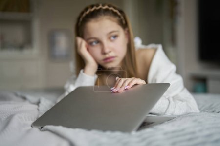 Infeliz adolescente chica cierre portátil acostado en la cama en casa ansioso por los medios sociales en línea intimidación y estar en línea demasiado 