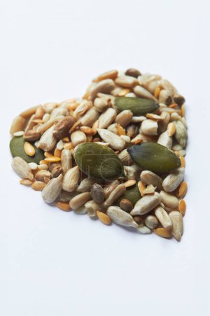 Foto de Inyección de alimentación saludable con frutos secos y semillas en forma de corazón sobre fondo blanco - Imagen libre de derechos