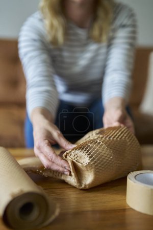 Photo for Woman Wrapping Parcel Protected With Green Environmentally Friendly Paper Or Plastic Free Honeycomb Packing Paper - Royalty Free Image