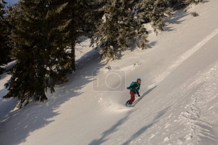 Photo for A female rider on a snowboard freeriding in a backcountry alpine terrain on an avalanche snowy slope, outdoor adrenaline adventure - Royalty Free Image