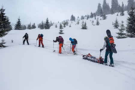 Photo for Ski rescuers pull a special sled (akya) in the mountains with the victim in the middle, an adrenaline outdoor adventures - Royalty Free Image