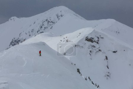 Photo for A skier descends a steep frozen slope in the mountains, an adrenaline outdoor adventures - Royalty Free Image
