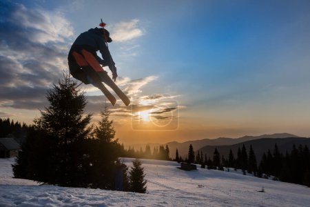 Photo for Freestyle extreme skier jumping from kicker in snowy mountains at orange sunset, an adrenaline outdoor adventures - Royalty Free Image