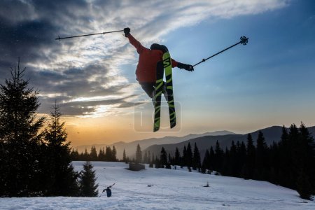 Photo for Marmaros, The Carpathians, UKRAINE - March 15 2021: freestyle extreme skier jumping from kicker in snowy mountains at orange sunset, an adrenaline outdoor adventures - Royalty Free Image