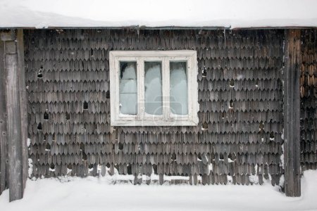 Photo for Old window of a old mountain hut and gray wooden wall covered with snow - Royalty Free Image