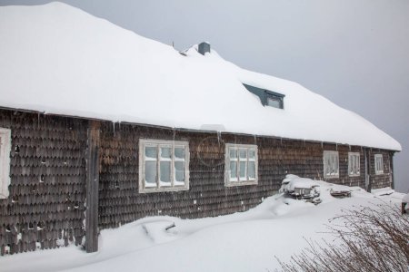 Téléchargez les photos : Old windows of a old mountain hut and gray wooden wall covered with snow. Meteorological observatory on Mount Pozhyzhevska, Chornohora - en image libre de droit