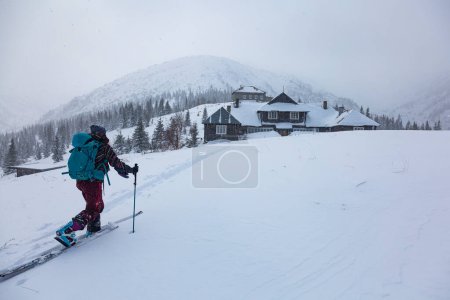 Téléchargez les photos : A skier hiker approaches a mountain house in a snow blizzard. Meteorological observatory on Mount Pozhyzhevska, Chornohora - en image libre de droit
