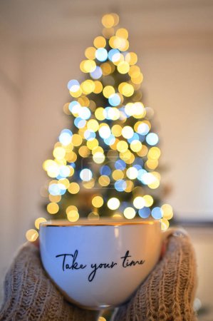 Foto de Conceptual Tómate tu tiempo Chica sosteniendo una taza de té y árbol de Navidad Bokeh - Imagen libre de derechos