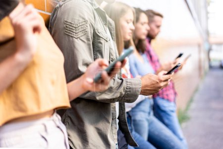 Gelangweilte Freunde sitzen mit Smartphone im Hinterhof der Universität - Junge Leute süchtig nach Handy - Technologie trauriges Lebenskonzept mit immer vernetzten Studenten - Kontrastfilter
