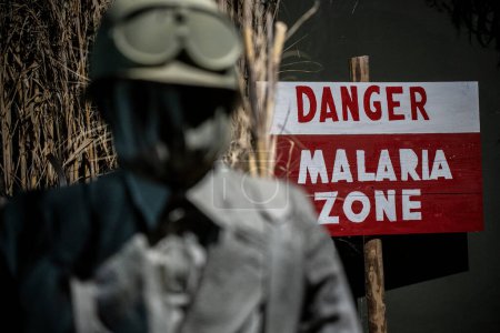 Téléchargez les photos : Signe de danger utilisé pendant la Seconde Guerre mondiale dans les zones de désinfestation du paludisme - À côté d'un homme en uniforme de l'époque avec un masque à gaz - en image libre de droit
