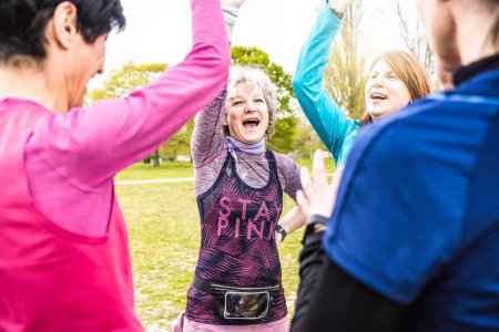 Photo for Happy multigenerational women stacking hands together before sport workout outdoor - Female friends having fun together outdoor at city park - Bright filter with focus on grey hair woman - Royalty Free Image