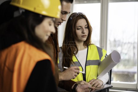 Téléchargez les photos : Ingénieur superviseur sur le chantier de construction avec son équipe de travail féminin définir des lignes directrices dans le bureau du chantier - Concept de travail d'équipe - en image libre de droit