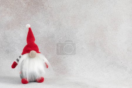 Foto de Gnomo hecho a mano de Navidad en bandera roja del día de fiesta del sombrero sobre fondo ligero del invierno. Tarjeta de felicitación de troll escandinavo con espacio para copiar - Imagen libre de derechos