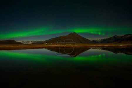 Foto de Aurora Borealis or Northern lights the amazing wonder of nature in the dramatic skies of Iceland. Night landscape with the green light in a beautiful dance reflected like a mirror - Imagen libre de derechos