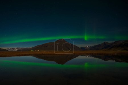 Foto de Aurora Boreal o auroras boreales la maravilla asombrosa de la naturaleza en los cielos dramáticos de Islandia. Paisaje nocturno con la luz verde en una hermosa danza reflejada como un espejo - Imagen libre de derechos