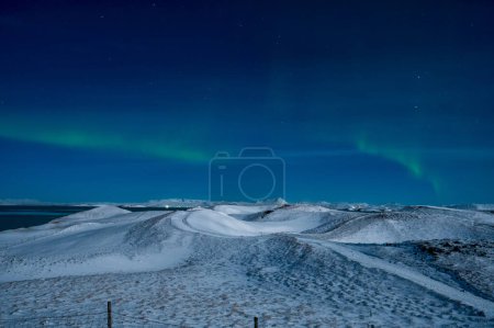 Foto de Aurora Boreal o auroras boreales la maravilla asombrosa de la naturaleza en los cielos dramáticos de Islandia. Paisaje nocturno con la luz verde y la blanca nieve del invierno - Imagen libre de derechos