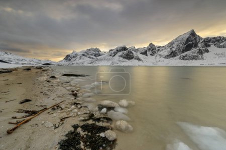 Foto de Islas Lofoten en Noruega y su hermoso paisaje de invierno al atardecer. Paisaje idílico en la playa cubierta de nieve. Atracción turística en el círculo ártico. Destino de viaje nórdico. - Imagen libre de derechos