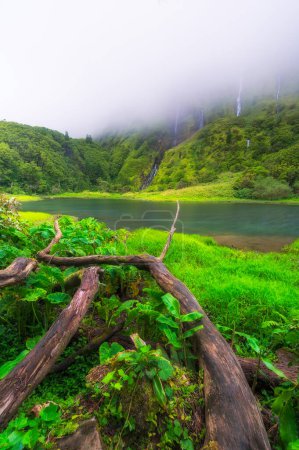 Azores scenic landscape, Flores island. Iconic lagoon with several waterfalls on a single rockface, flowing into lake Alagoinha. Best travel destination in Portugal, amazing vacations place.