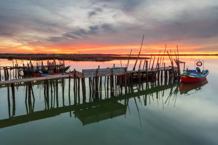 Atemberaubender Sonnenuntergang auf dem Pier von Carrasqueira, Alentejo, Portugal. Holzhandwerklicher Fischerhafen mit traditionellen Booten auf dem Fluss Sado. fineart farbige horizontale Fotografie.